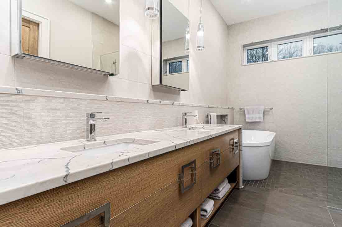 Modern bathroom with long white double vanity, wall mirror, toilet, and tiled floor