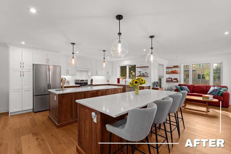 Bright open-plan kitchen with white island, stainless fridge, pendant lights, and red sofa in living area
