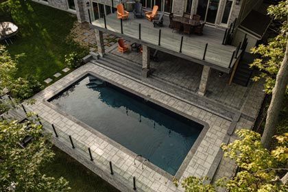 Backyard patio with a rectangular swimming pool and deck chairs beside a house
