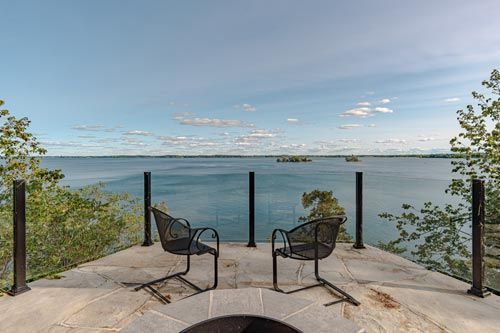 Patio with two chairs overlooking a calm lake under a blue sky