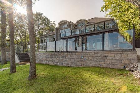 Modern stone building with large windows beside a grassy lawn and trees in sunlight