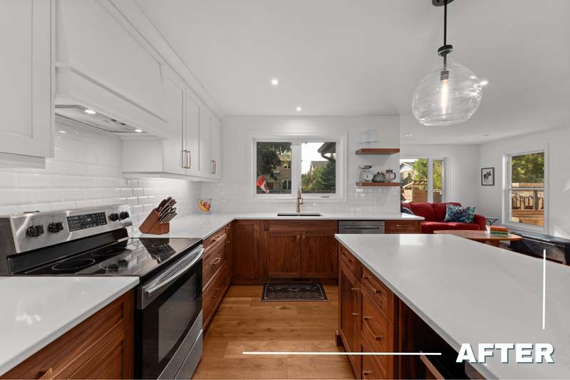 Bright modern white kitchen with wood island, stainless stove, pendant light, and open living area beyond.