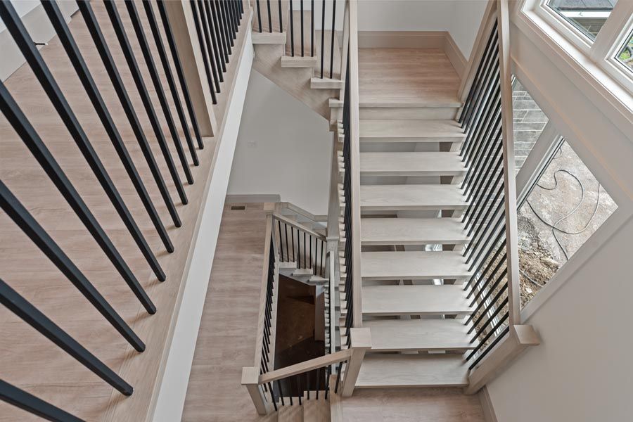 Stairwell interior with light wood steps, black railings, and a zigzag staircase view.