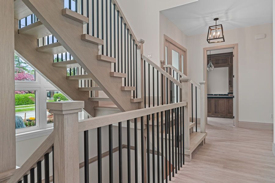 Modern home entry hall with staircase, gray railings, and light wood floors
