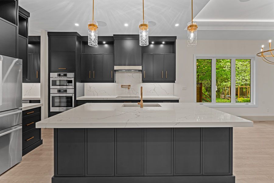 Modern kitchen with dark cabinets, large island, pendant lights, and white countertops