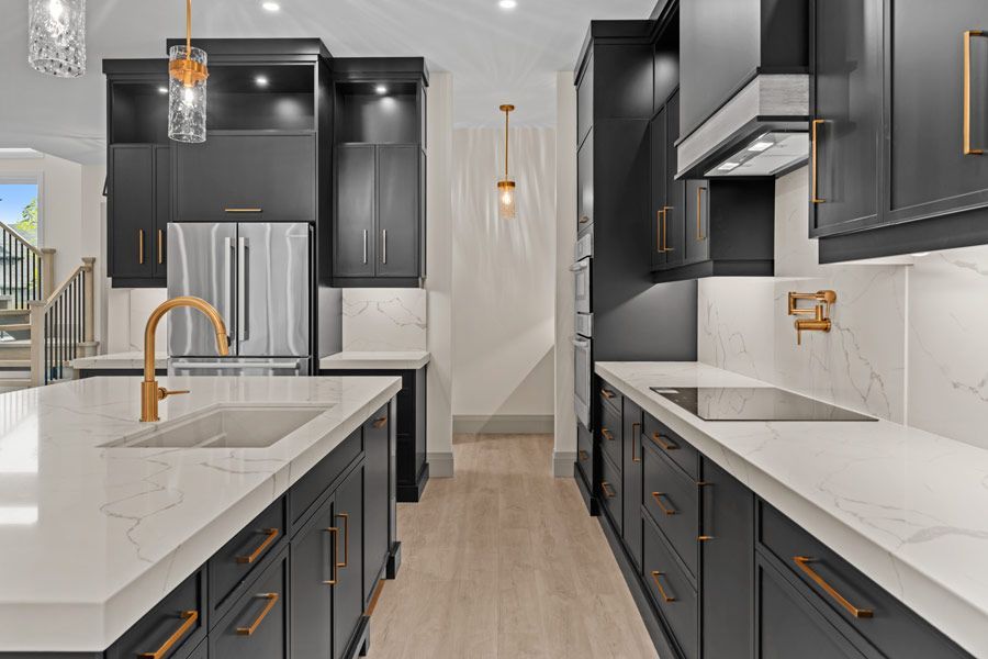Modern black-and-white kitchen with gold fixtures, white countertops, and stainless steel appliances