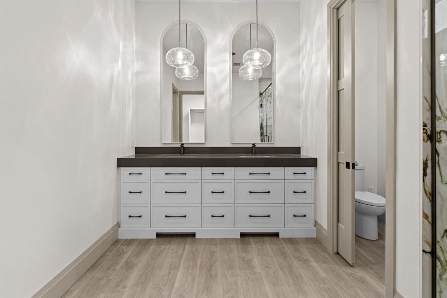 Modern bathroom vanity with double sinks, arched mirrors, pendant lights, and a walk-in shower