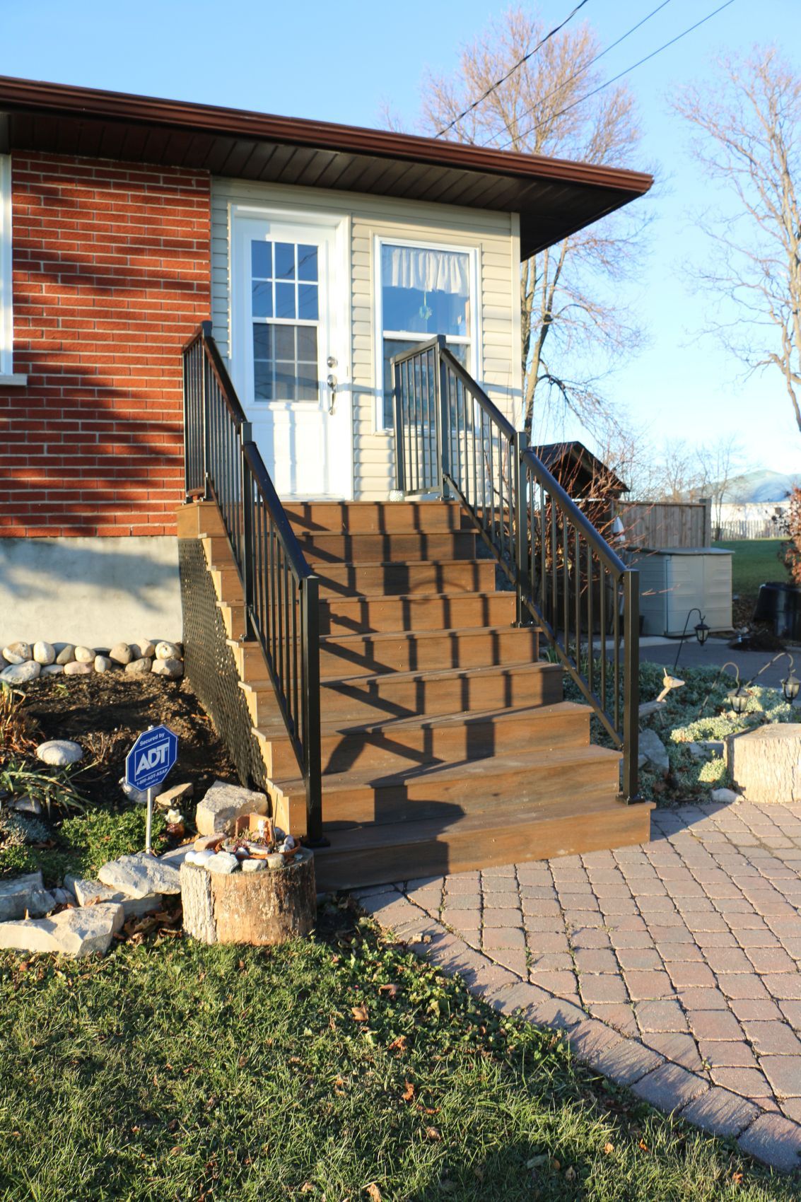 Front steps with wooden railings leading to a white double door on a brick house