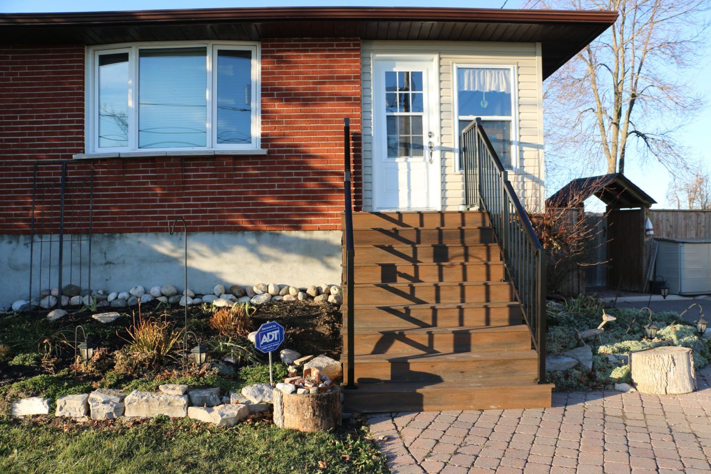 Front steps with black railings leading to a white door on a brick house