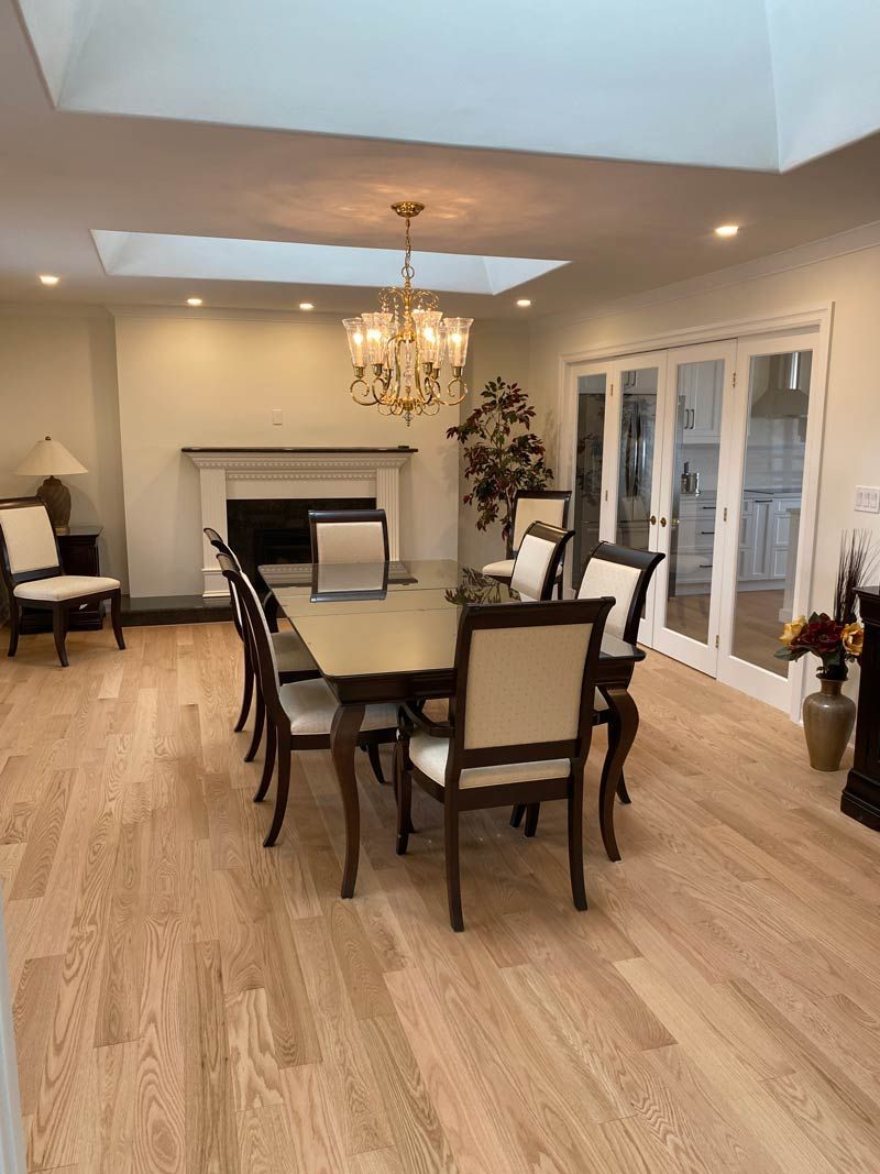 Elegant dining room with chandelier, dark wood table, cream chairs, fireplace, and French doors to the right