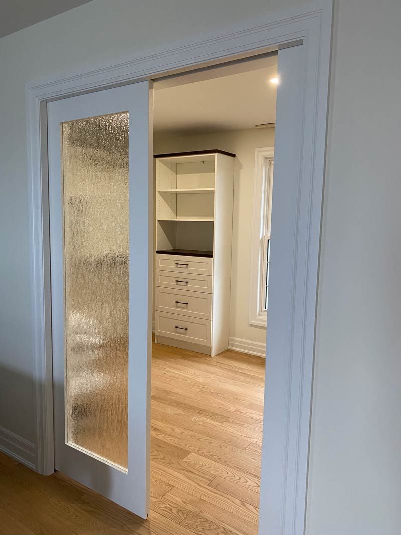 White-framed glass sliding doors open to a bright room with wood floors and built-in shelves.