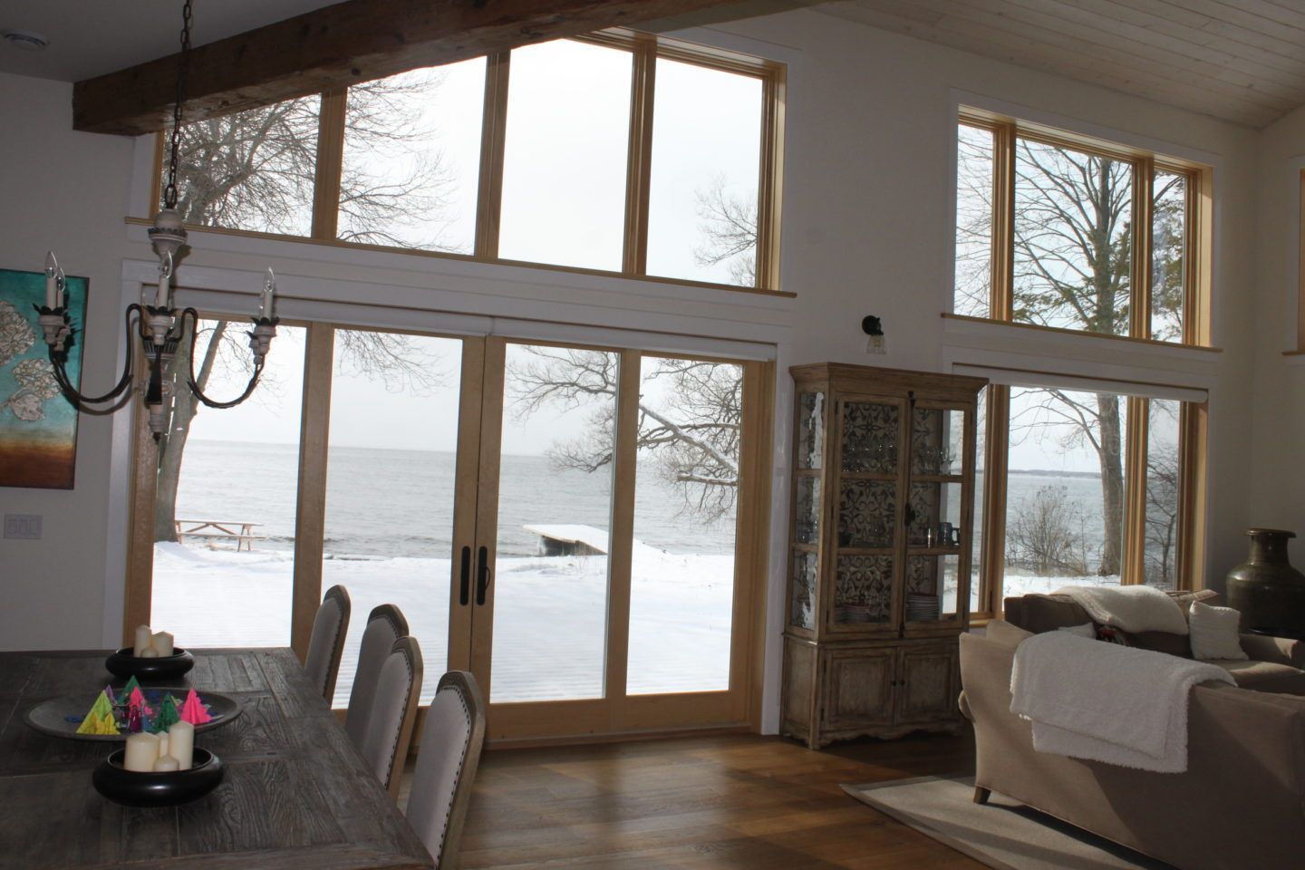Bright living room with large windows, sliding glass doors, dining table, and snowy view outside