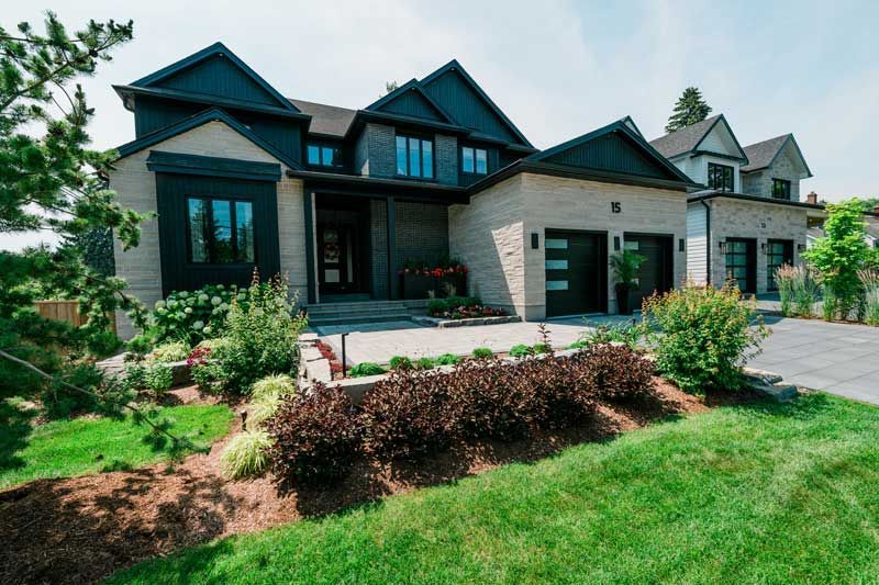 Modern black-and-gray house with a landscaped front yard and driveway