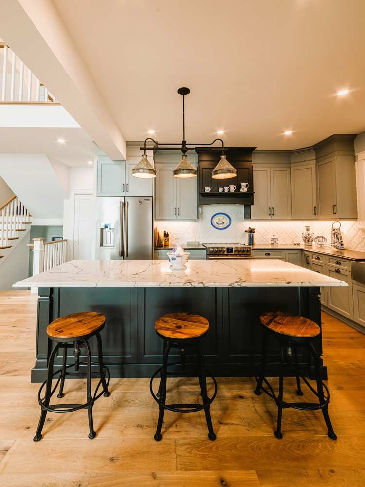 Modern kitchen with a large island, black stools, pendant lights, and stainless steel appliances