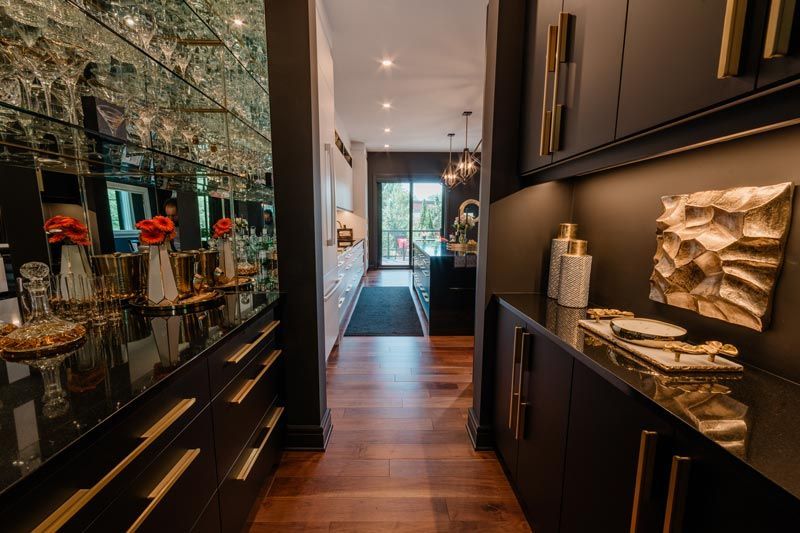 Elegant hallway with dark cabinets, mirrored wall, warm wood floor, and decorative accents