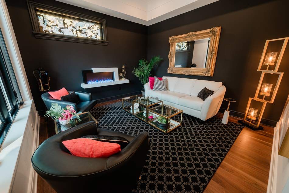 Stylish living room with black walls, white sofa, round chair, coffee table, and decorative lighting