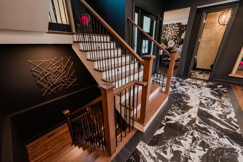 Modern stairwell with black-and-white marble floor, wooden railings, and decorative wall art
