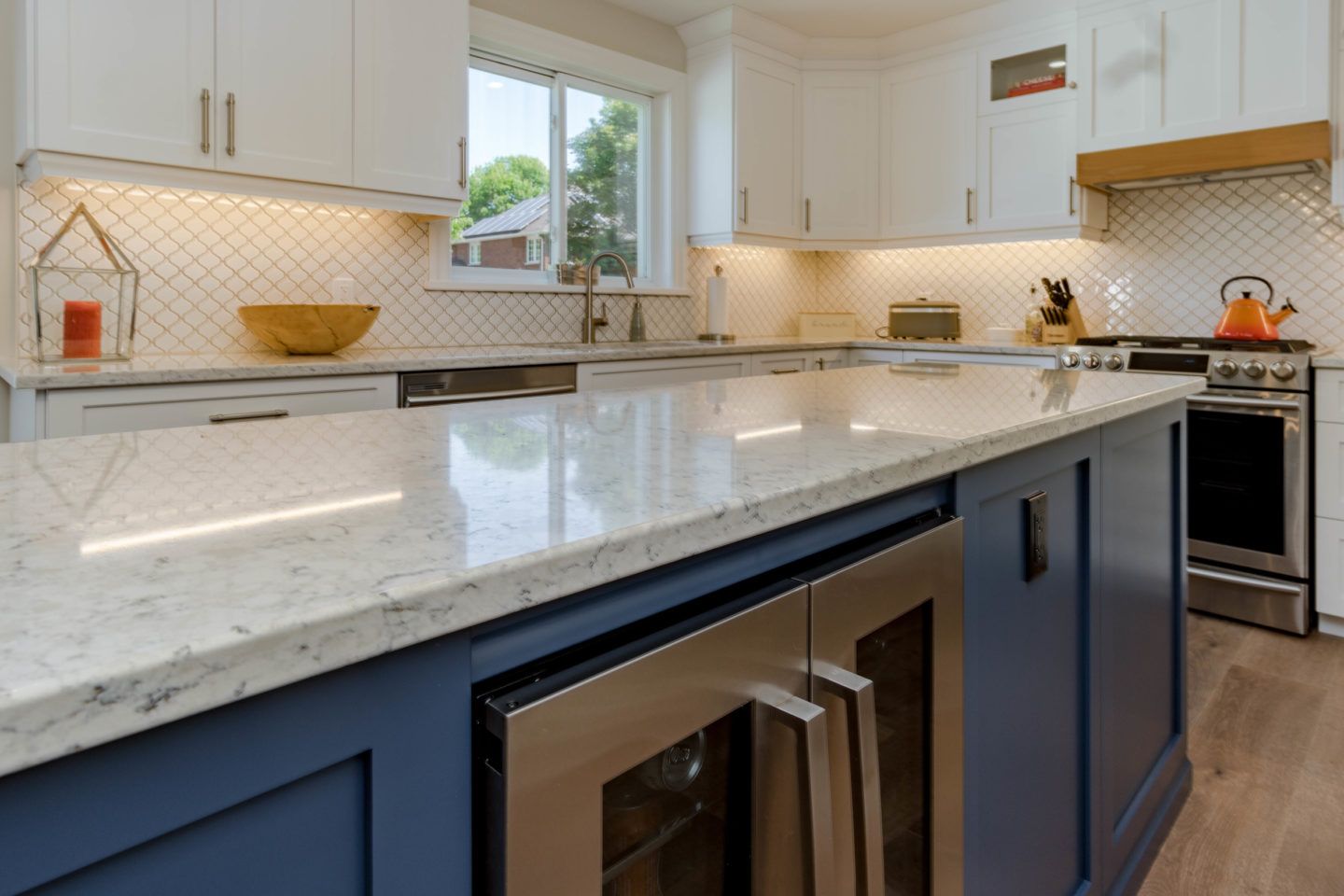 Bright modern kitchen with white cabinets, marble island, and blue lower cabinets