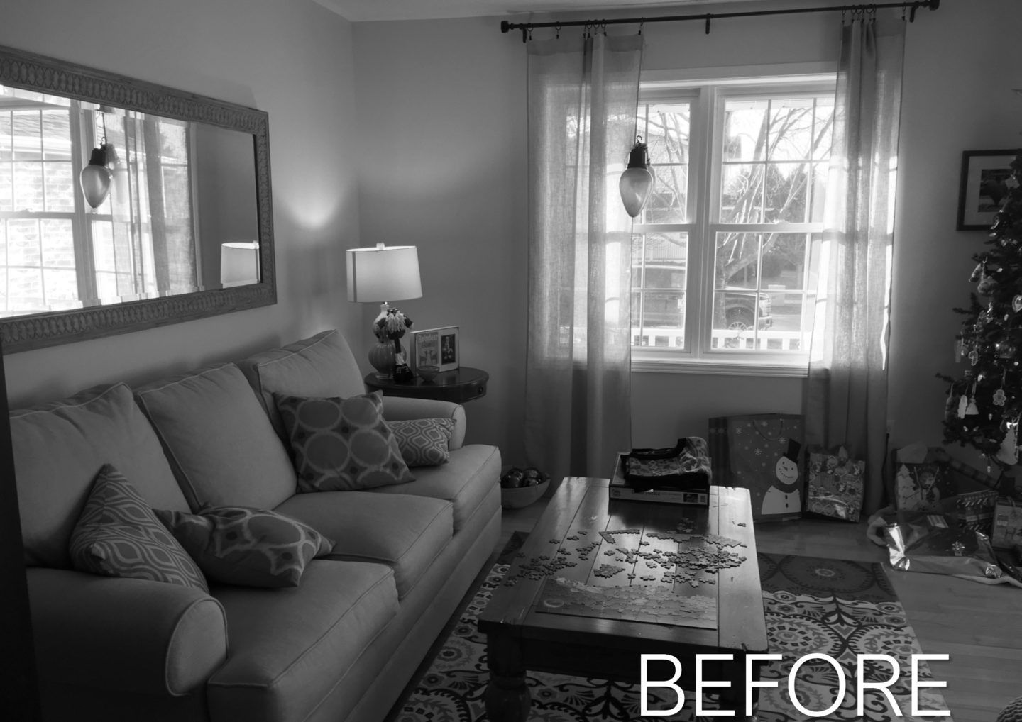 Living room with sofa, lamp, window, rug, and Christmas tree; “BEFORE” text at bottom right