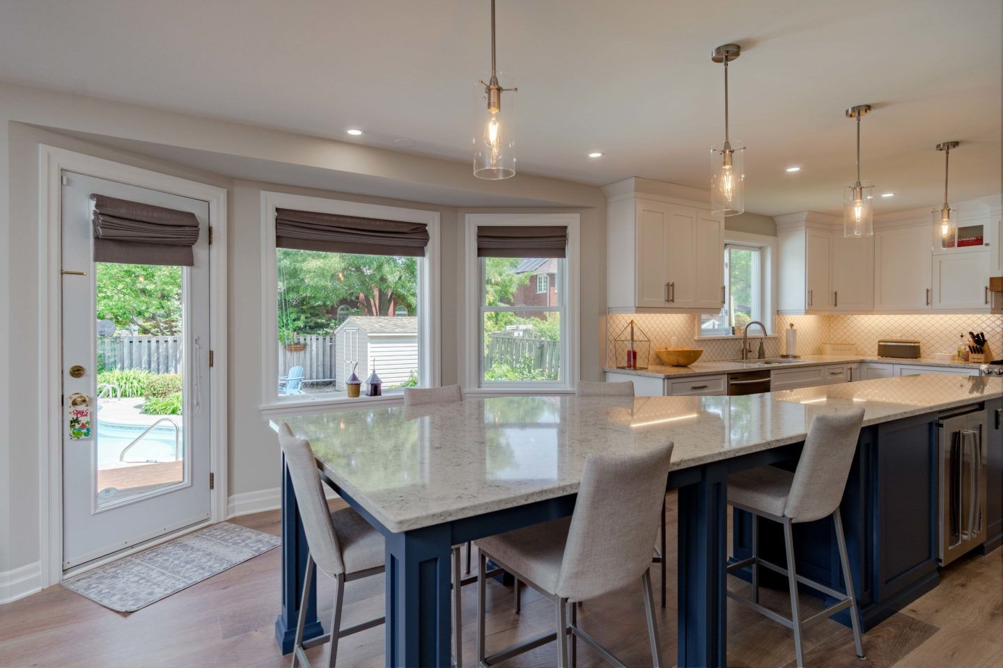 Bright modern kitchen and dining area with island seating, pendant lights, and sliding glass doors to a patio.