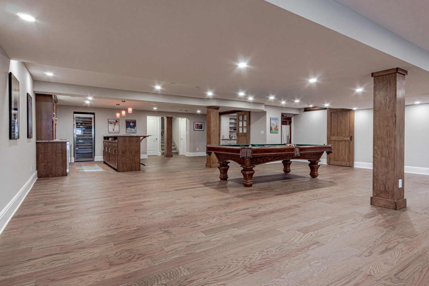 Spacious finished basement with wood floors, recessed lighting, bar area, and pool table