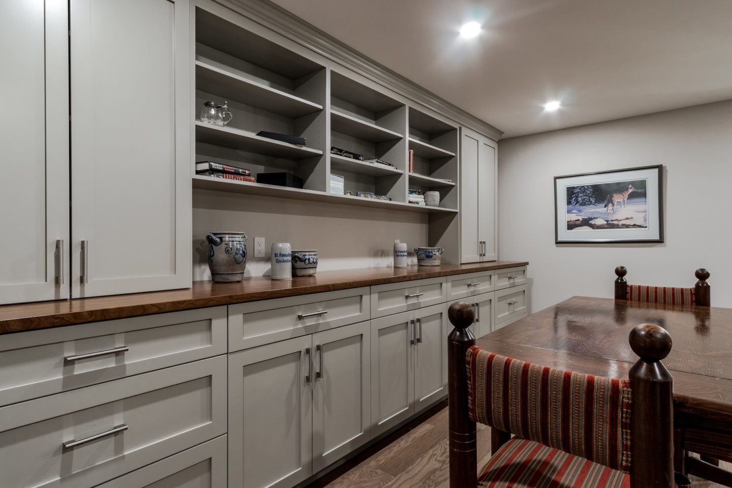 Built-in kitchen cabinets and shelves along a dining area with a wooden table and chairs