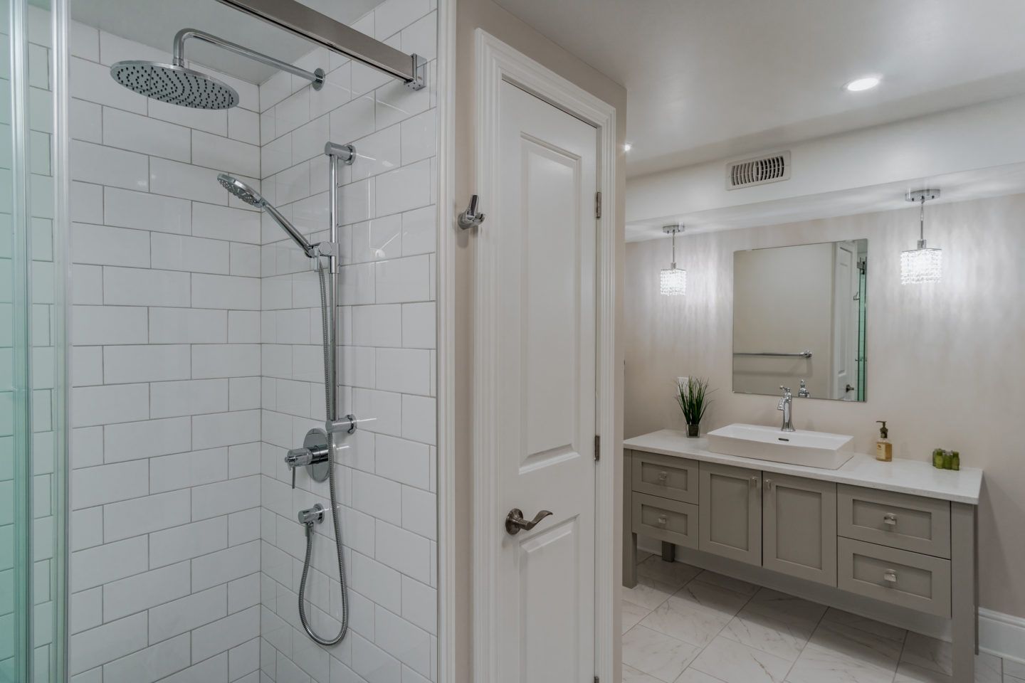 White tiled bathroom with walk-in shower, vanity, and large mirror
