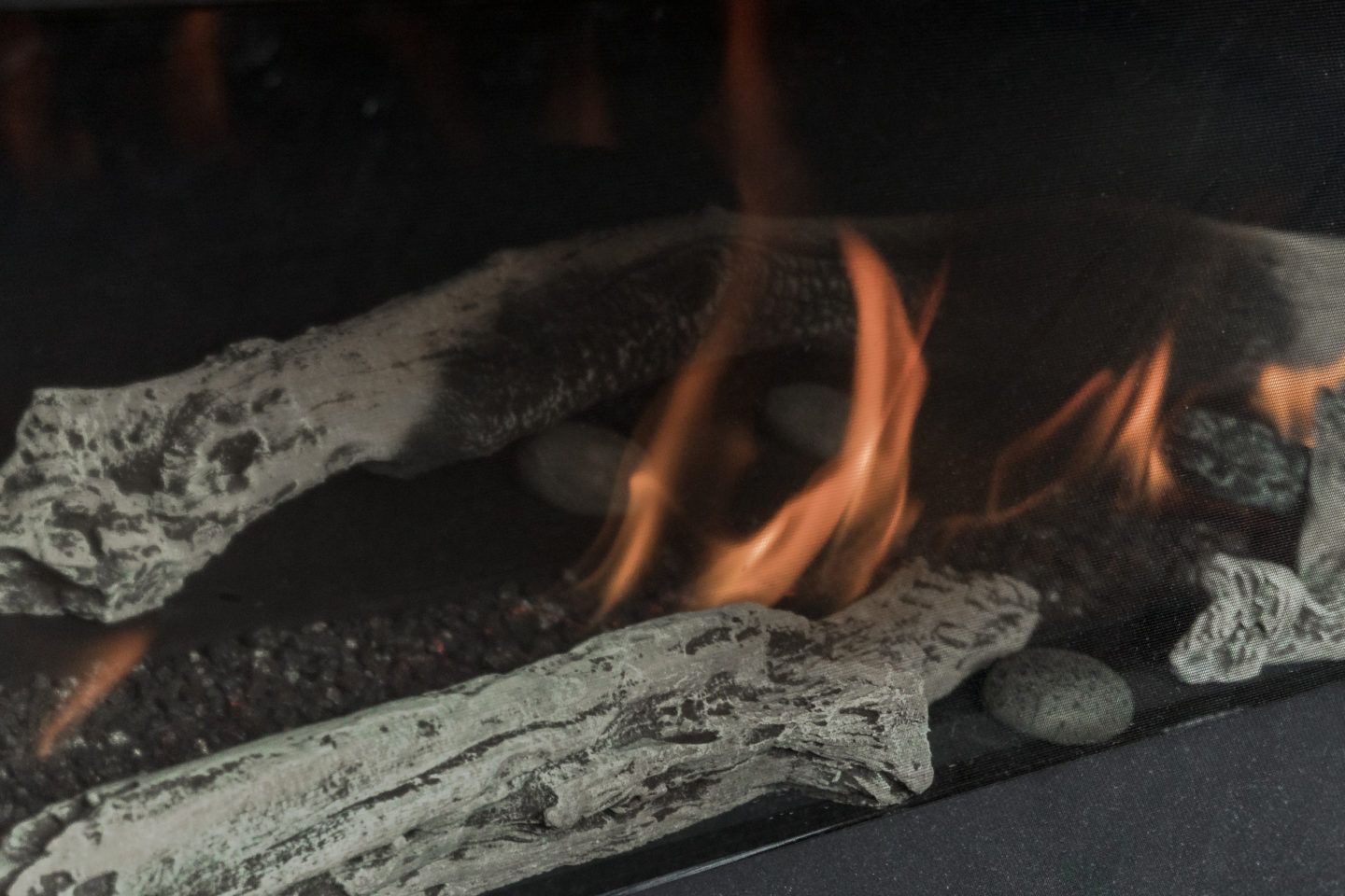 Close-up of orange flames burning over charred logs in a fireplace