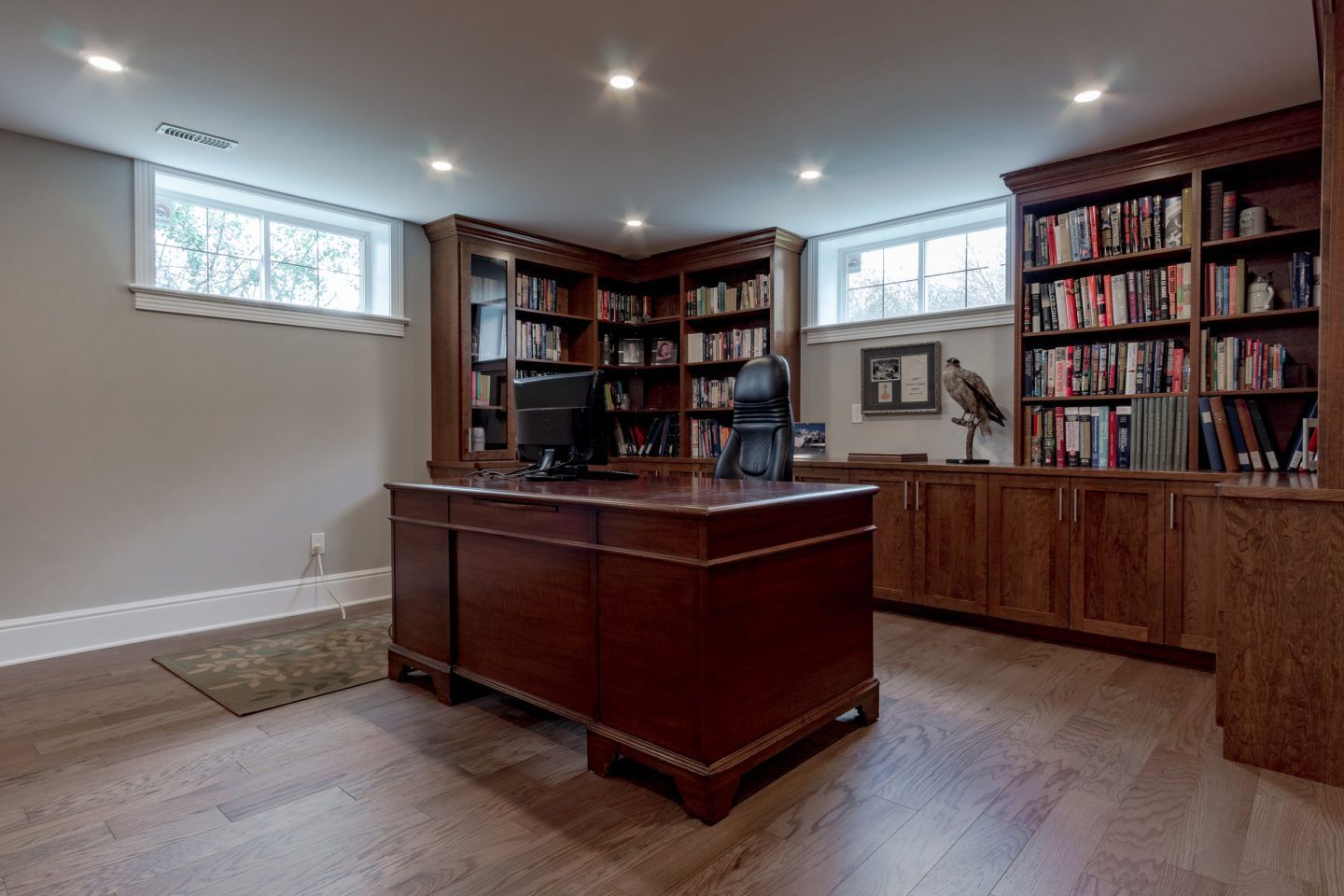Home office with wooden desk, bookcases, and recessed lighting in a finished basement room