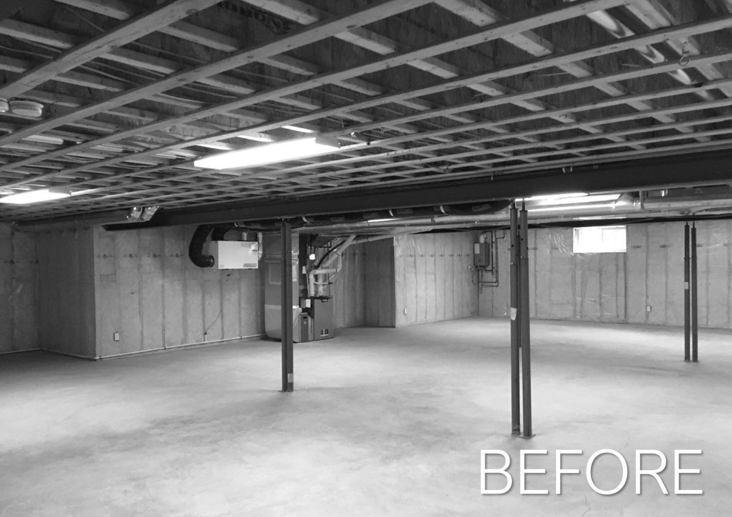 Empty unfinished basement with exposed ceiling, support posts, and bare concrete floor, labeled “BEFORE”