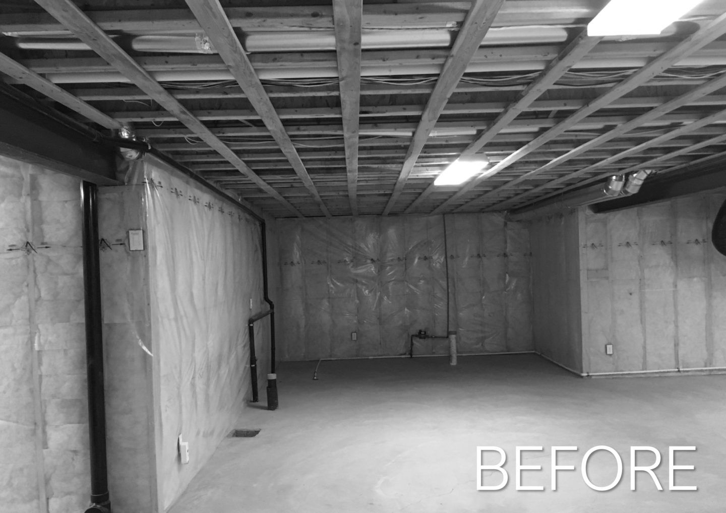 Empty unfinished basement with exposed ceiling beams and concrete walls, labeled “BEFORE”