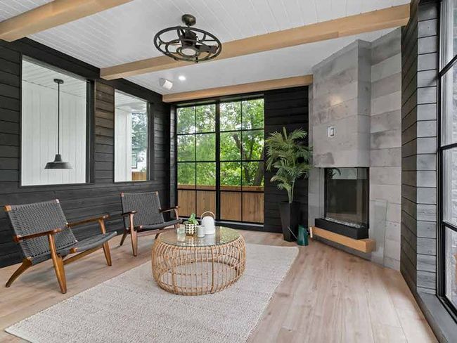 Modern covered patio with wicker chairs, coffee table, fireplace, and large windowed doors