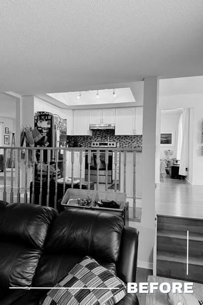 Living room before renovation, with sofa in foreground and open view to kitchen and hallway