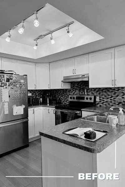 Black-and-white photo of a modern kitchen with island, refrigerator, stove, and skylight.
