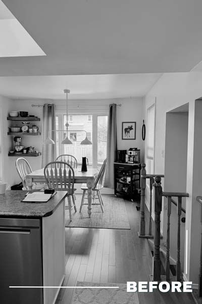Black-and-white view of a kitchen and dining area with a table, chairs, pendant lights, and a rug