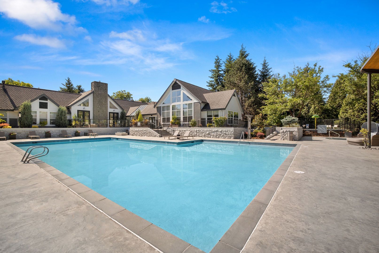 Outdoor community pool with surrounding deck and clubhouse buildings.