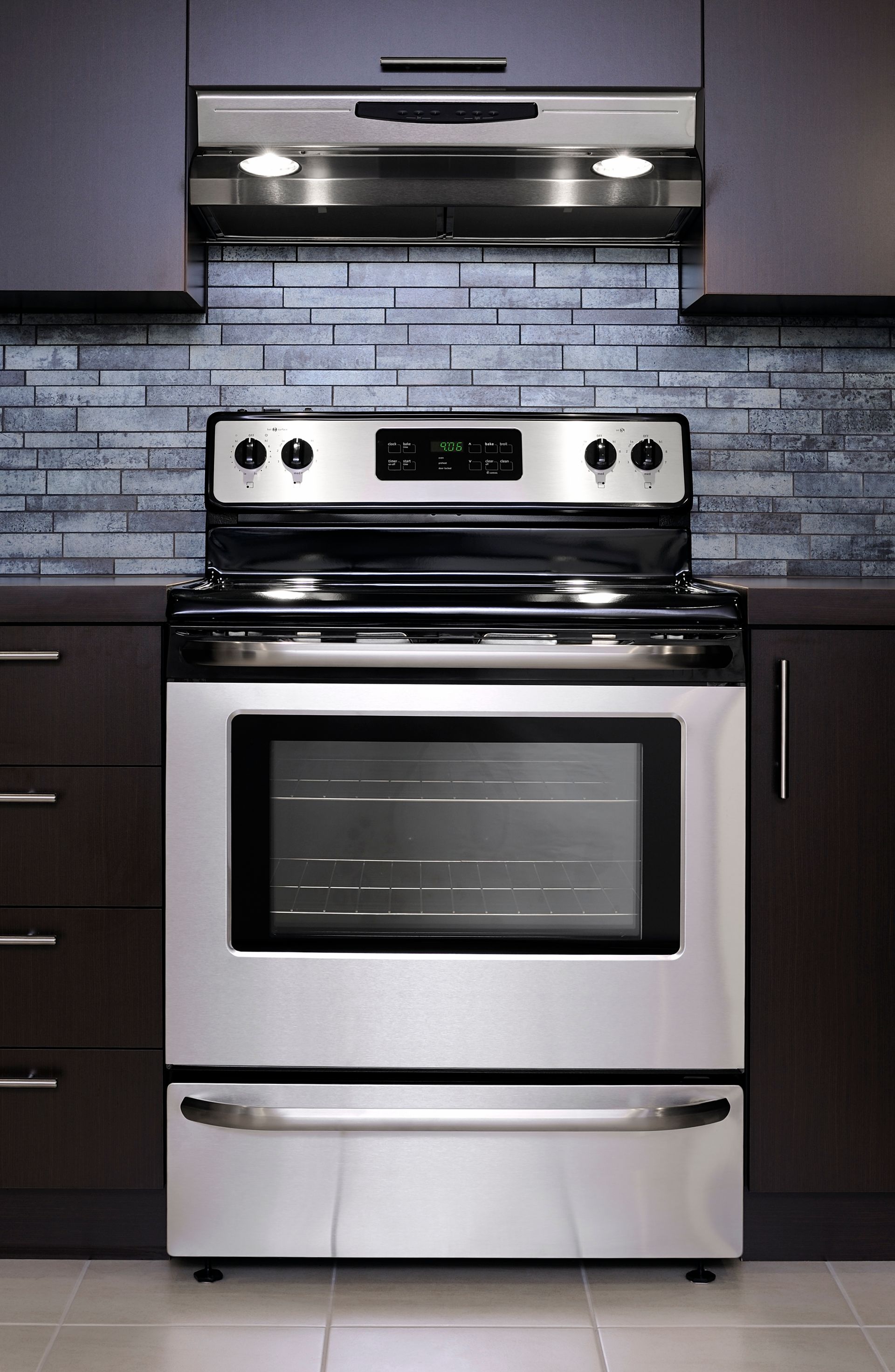 A stove in a kitchen with a brick wall behind it