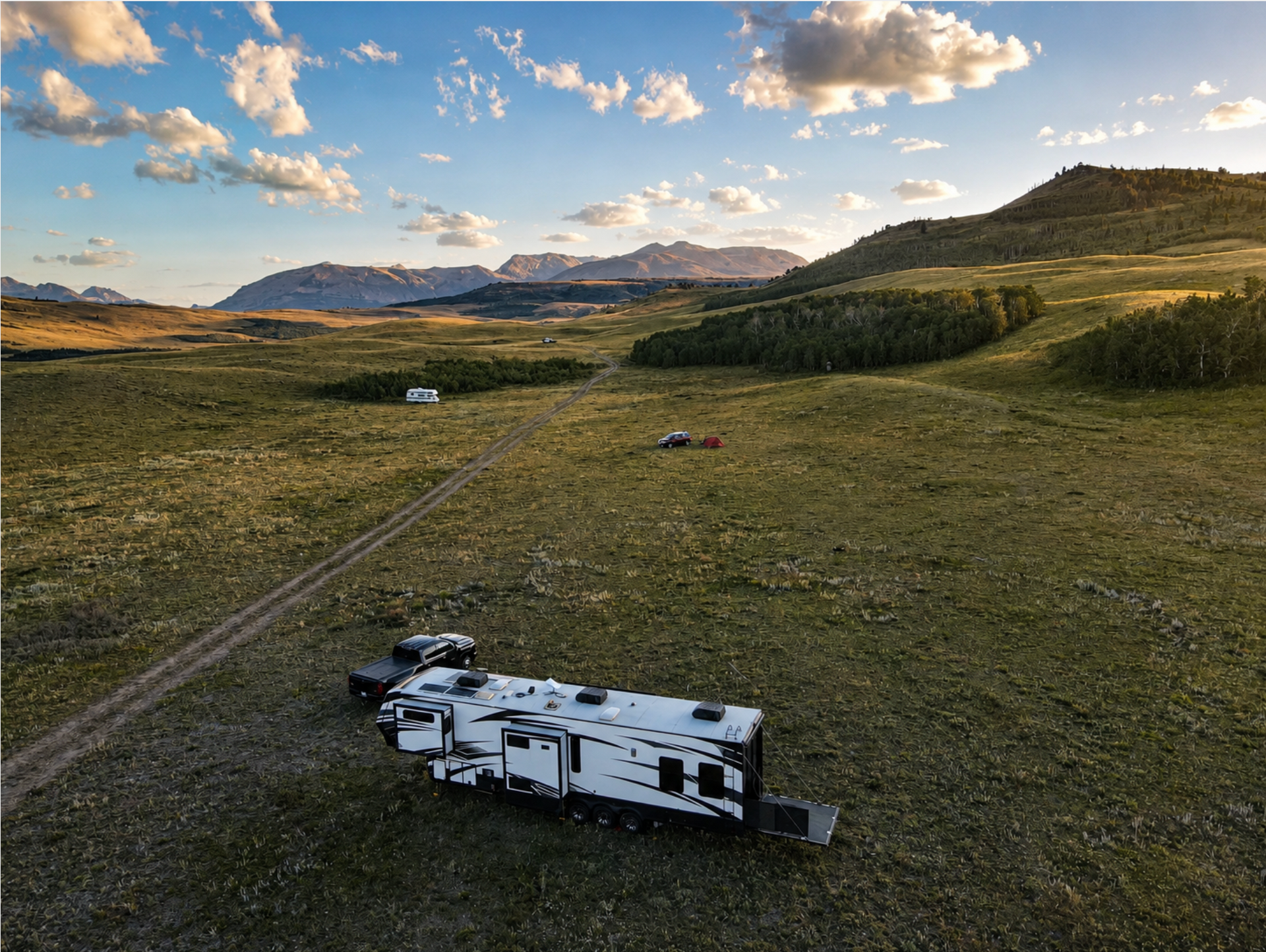 RV trailer tipped on its side in a grassy field under a cloudy sunset sky.