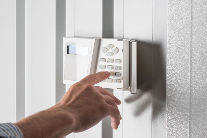 Mano che preme i pulsanti su una tastiera di sicurezza bianca montata a parete.