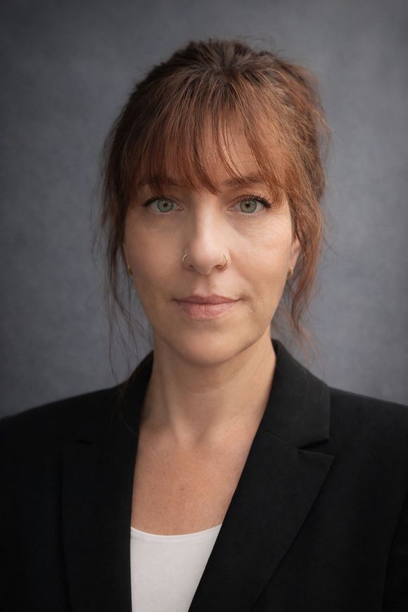 Studio portrait of a woman in a black blazer against a gray background