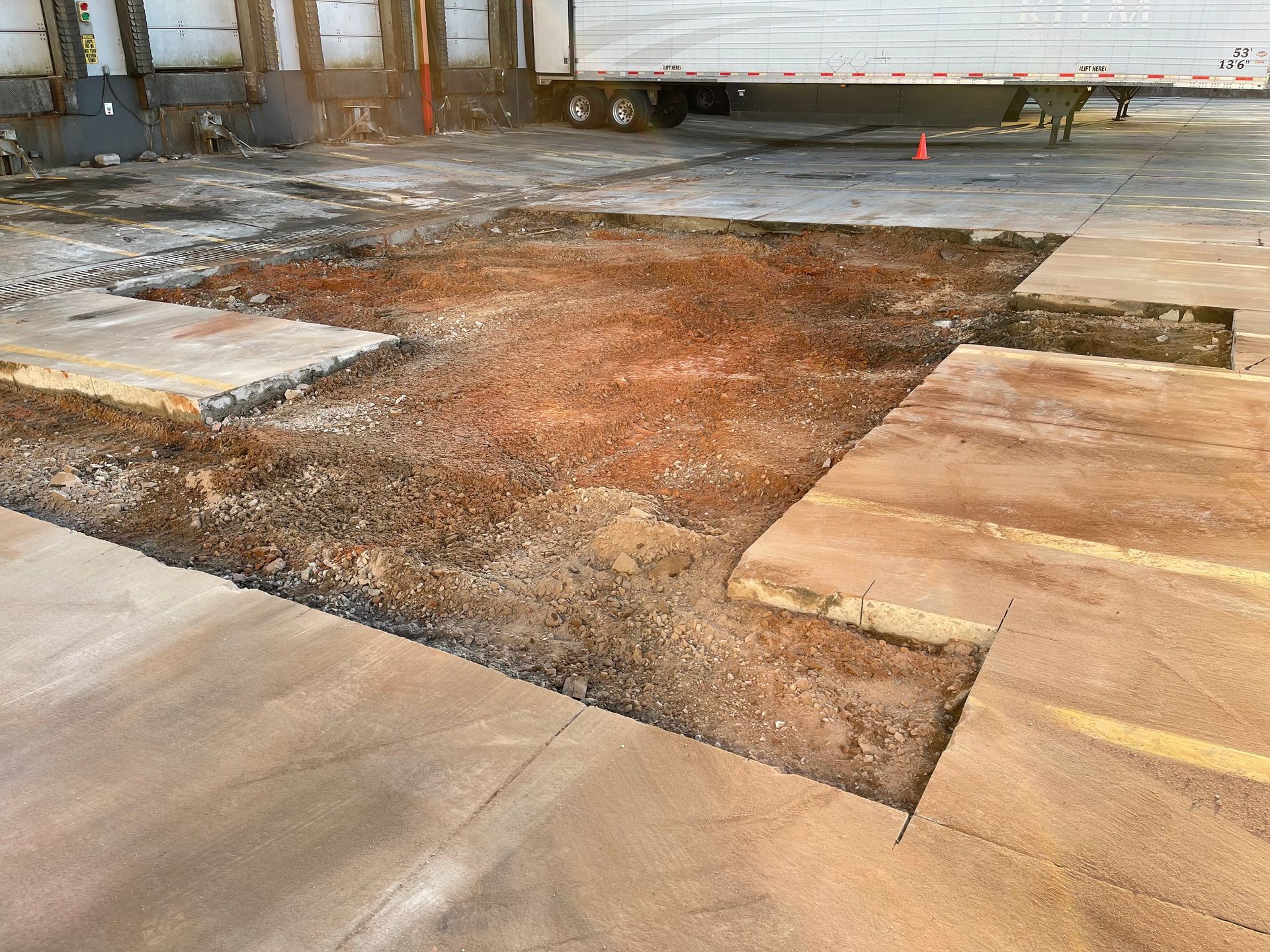 Construction site floor with broken concrete slabs and exposed dirt in the center