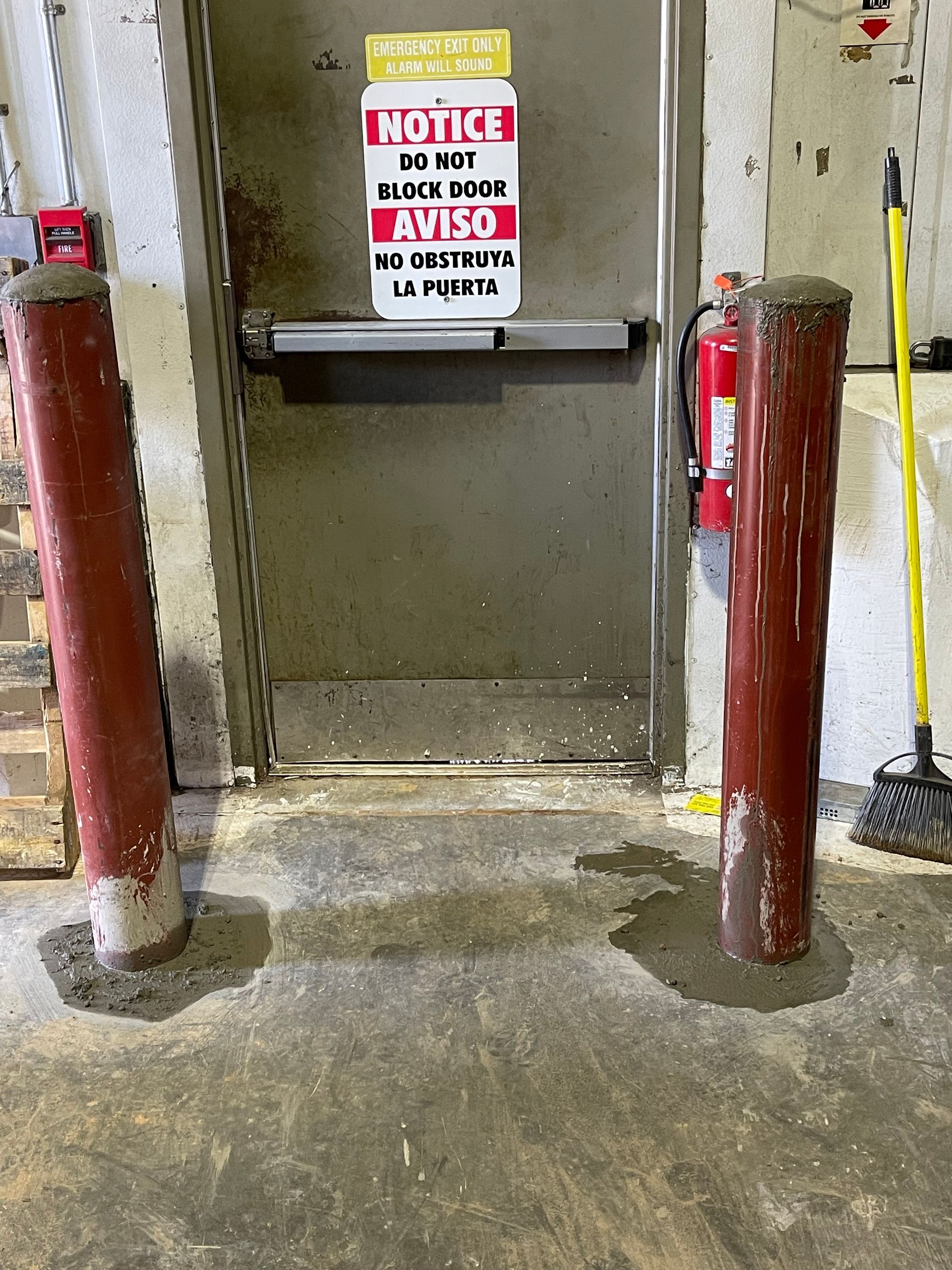 Two bollards and an open doorway with warning signs in an industrial area