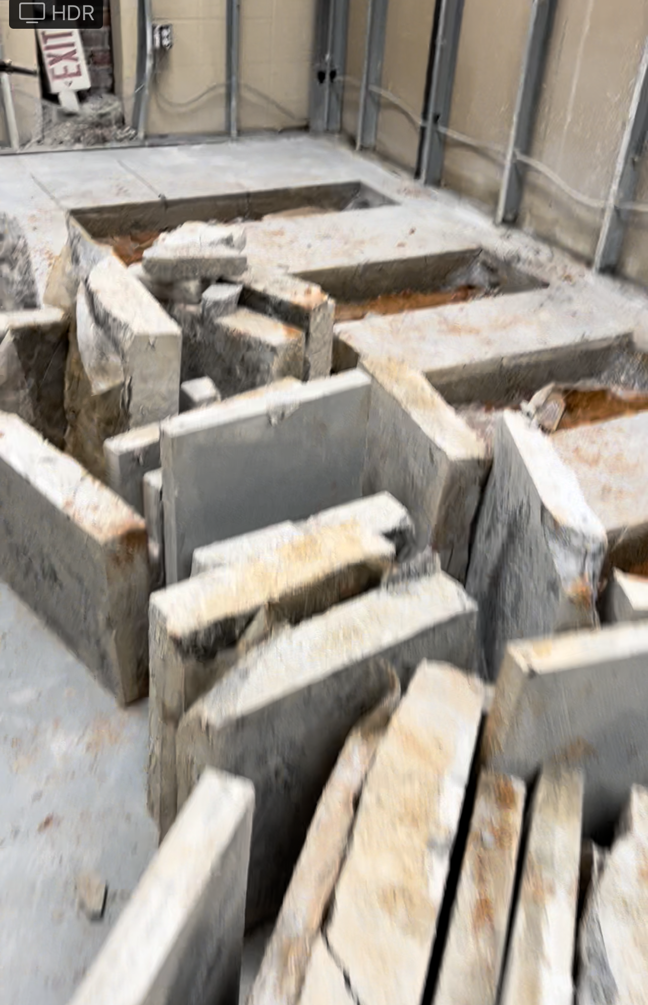 Two construction workers are using a jackhammer to drill a hole in the ground.