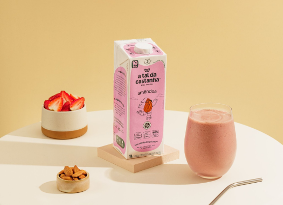 Caixa de leite de amêndoa com morango e smoothie com morangos e amêndoas sobre uma mesa.