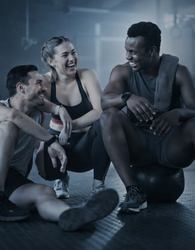 Três pessoas rindo em uma academia após o treino.