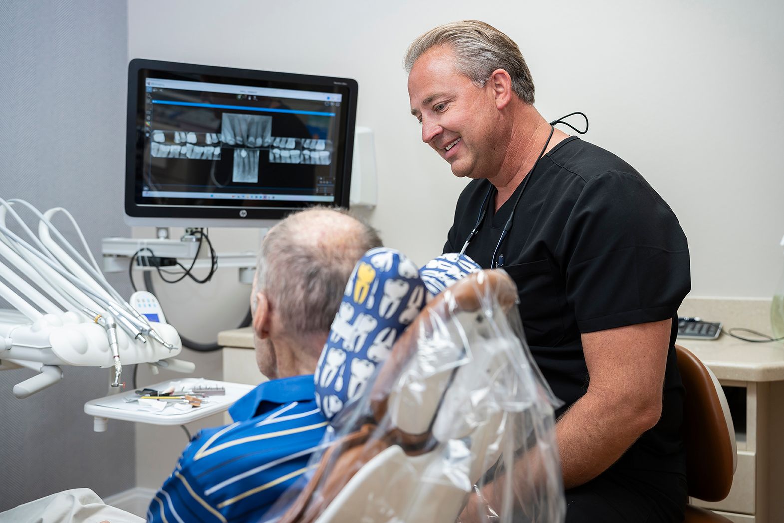 Dr. Maley is talking to a patient in a dental chair at Maley Family Dental