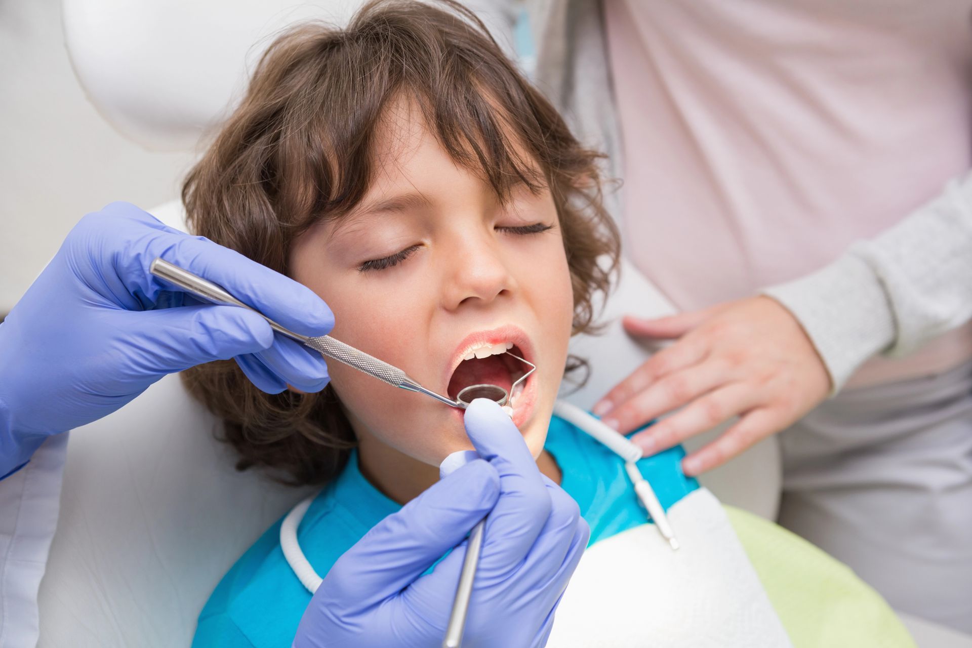 A young boy is getting his teeth examined by a dentist.