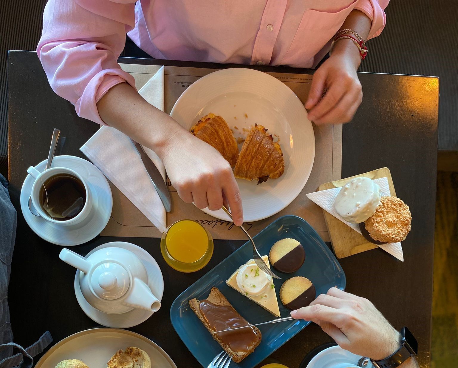 Dos personas están sentadas en una mesa con platos de comida y bebidas.