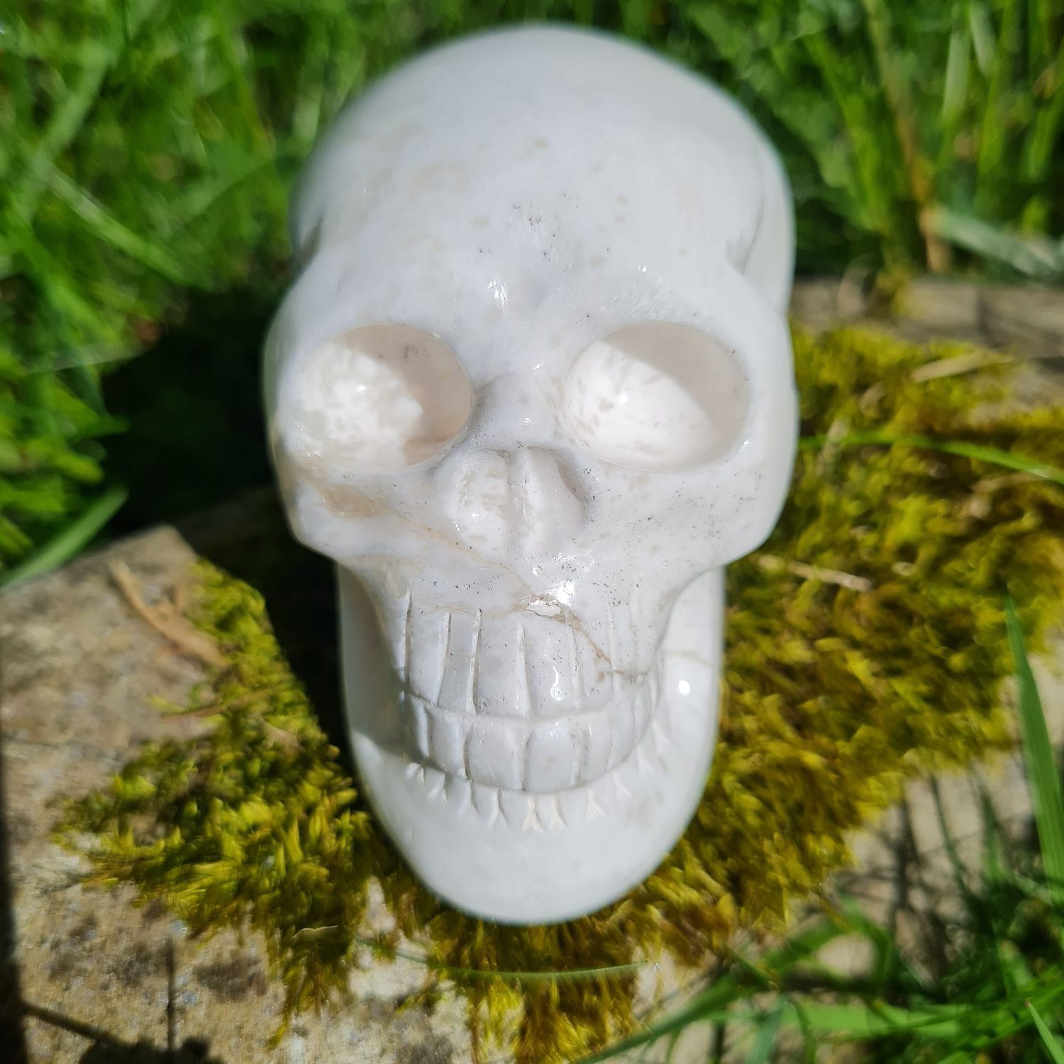 Scolecite crystal skull on moss and rock outside