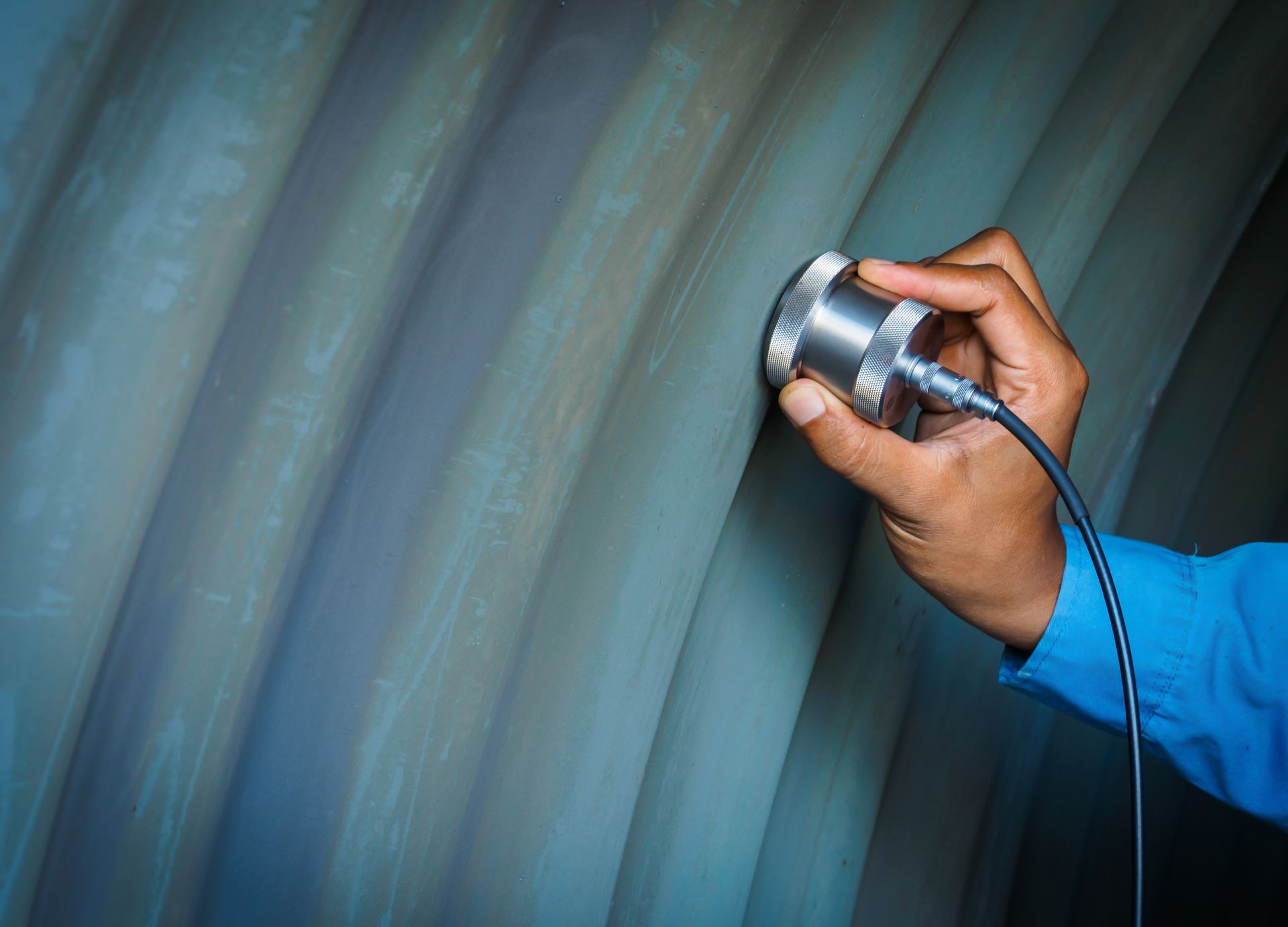 A person is using a magnetic detector on a piece of metal.